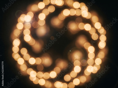 Obraz na plátně Golden bokeh lights in circular pattern, warm glowing amber light orbs on black