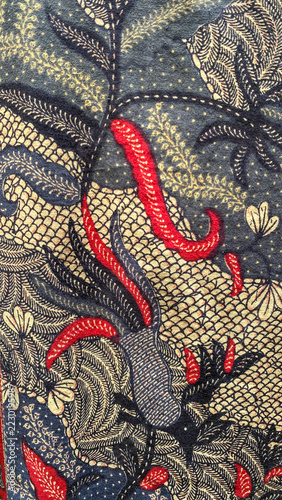 Richly patterned batik fabric featuring intricate floral embroidery on a deep blue background