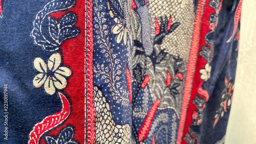 Richly patterned batik fabric featuring intricate floral embroidery on a deep blue background