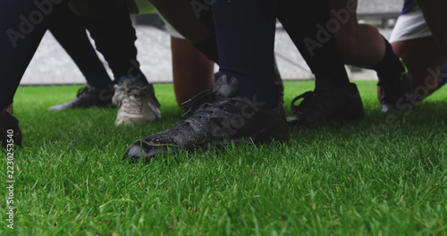 Feet of rugby players in scrum on pitch at stadium