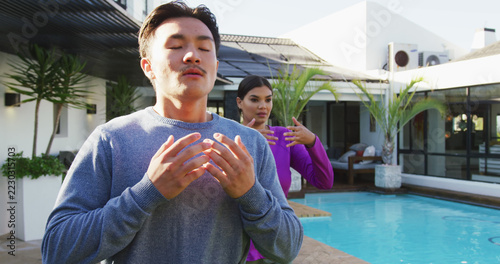 Image of relaxed diverse couple exercising tai chi in garden