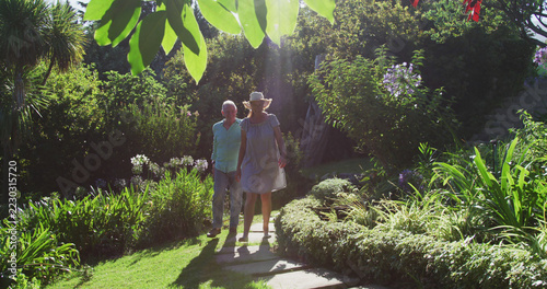Caucasian senior couple walking in garden together in the sun