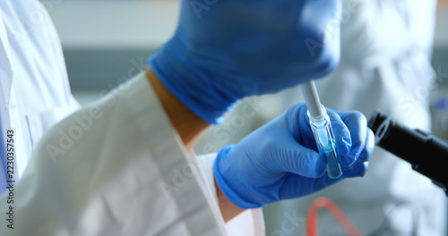 A scientist pipettes a sample in a laboratory setting