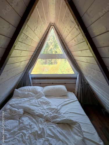 Wooden attic bedroom in A-frame cabin