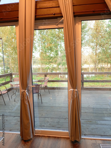 Wooden terrace with a view from the window to the garden in a glamping pod.