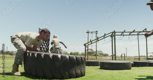 A fit soldier trains by flipping a tire outdoors, embodying a vigorous military lifestyle.