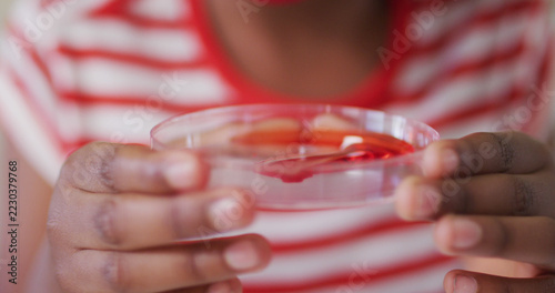 Schoolgirl wearing face mask, looking at a liquid