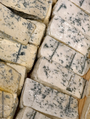 Fotografie Blue mold cheese pieces wrapped in transparent food wrap, showing sliced dairy p