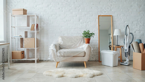 Armchair covered in plastic next to moving boxes and vacuum cleaner