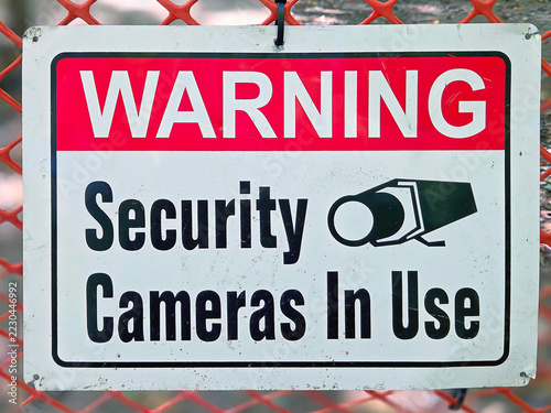 A bold black-and-white warning sign alerts visitors that security cameras are monitoring the area 