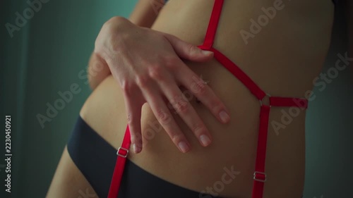 closeup of woman in black lingerie and red bdsm harness straps indoor portrait, female model posing with adult body accessories 4k
