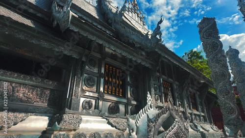 intricate Silver Temple architecture displaying carved metal relief, detailed Chiang Mai buddhist shrine Wat Sri Suphan exterior featuring traditional asian handmade ornament 4k