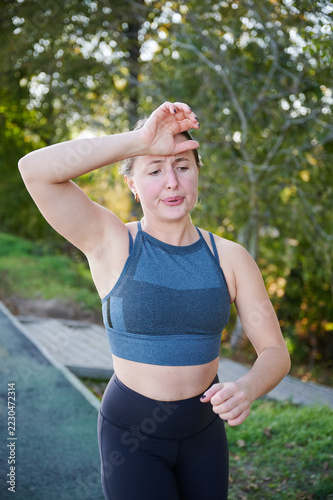 Fotografie Woman wiping sweat from forehead during run