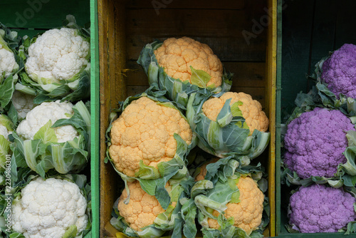 Сolorful white orange and purple cauliflower displayed in wooden crates at market