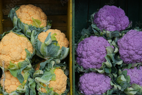Сolorful white orange and purple cauliflower displayed in wooden crates at market