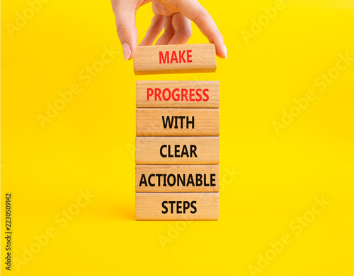 Make progress with clear actionable steps symbol. Concept words make progress with clear actionable steps on wooden blocks. Businessman hand. Beautiful yellow background. Business concept. Copy space.