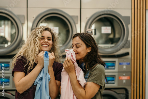 Women smelling clean fresh laundry in laundromat