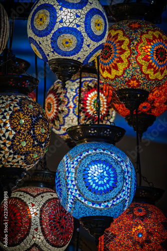 Colorful mosaic glass pendant lamps with intricate geometric patterns in a market display. Turkish handcrafted lighting decor. Traditional artisan craftsmanship and interior design.