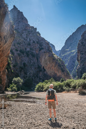 Hiker exploring the towering limestone gorge of Torrent de Pareis in Mallorca, Spain