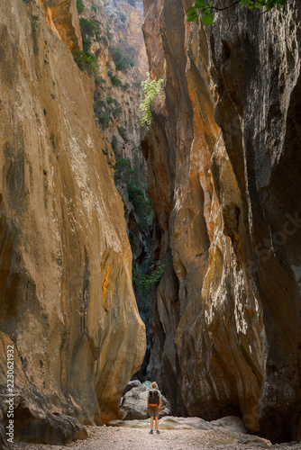 Hiker exploring the towering limestone gorge of Torrent de Pareis in Mallorca, Spain