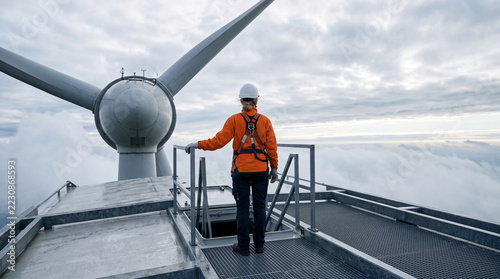 Technician at open hatch on top of wind turbine nacelle people staff renewable energy
