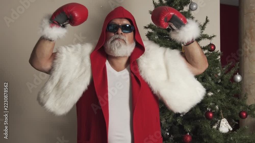 Boxer Santa raises gloves and takes fighting stance beside Christmas tree