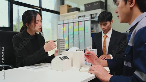 Professional engineers and architects discussing urban development and construction projects with building models and blueprints in a modern office.