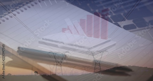 Displaying spiral-bound notebook with pen on desk, overlaying laptop keyboard, 3D bar chart, towers