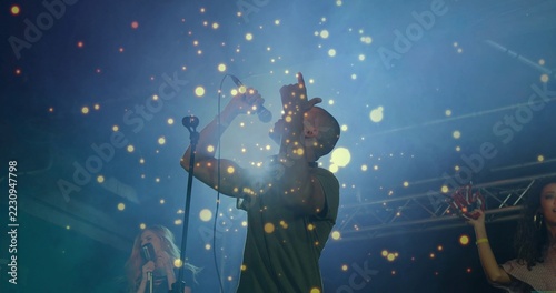 Singing lead singer wearing dark short-sleeve shirt on concert stage with microphones, truss, haze