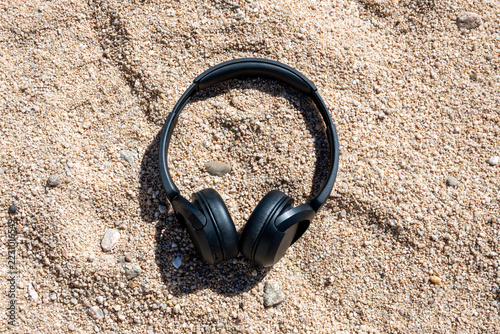Wireless headphones resting on textured beach sand