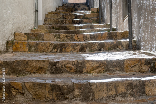 Stone old steps climb through a narrow historic alley in sunlight