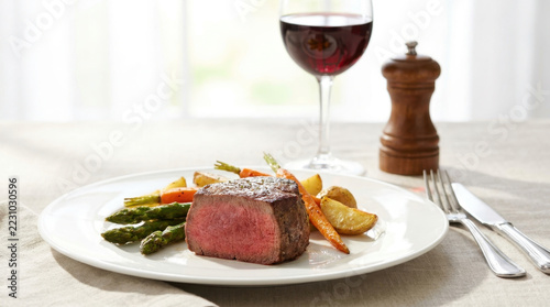 Top view of sliced medium-rare grilled steak with melting butter and rosemary on a dark rustic wooden background