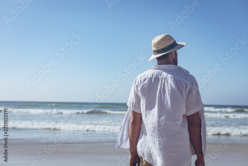 Handsome man standing at beach on sunny day