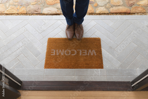 Man standing near welcome mat in front of door at home