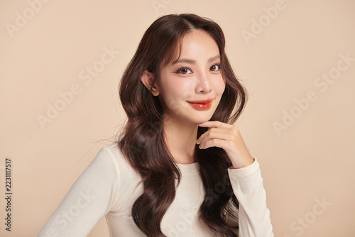A beautiful young Asian woman with clean, fresh skin against a beige background. Skincare, facial treatment, cosmetology, beauty, and spa. An elegant portrait of an Asian woman.