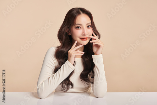 A beautiful young Asian woman with clean, fresh skin against a beige background. Skincare, facial treatment, cosmetology, beauty, and spa. An elegant portrait of an Asian woman.