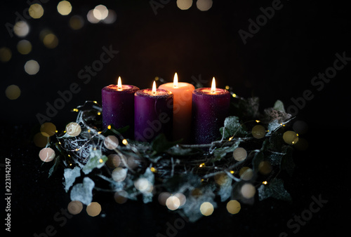 Four burning Advent candles in Christmas wreath during holiday season.