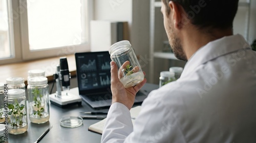 Scientist Analyzing Plant Growth in Laboratory with Modern Equipment and Data Charts