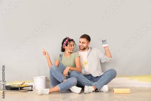 Home renovation and diy project, happy young couple sitting on floor painting...