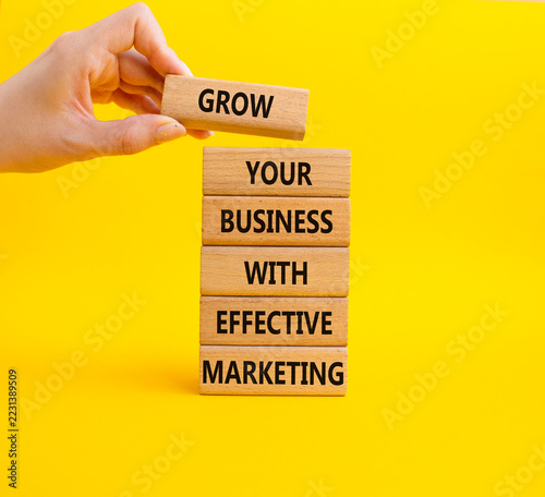  Concept words grow your business with effective marketing on wooden blocks. Businessman hand. Beautiful yellow background. Business concept. Copy space.