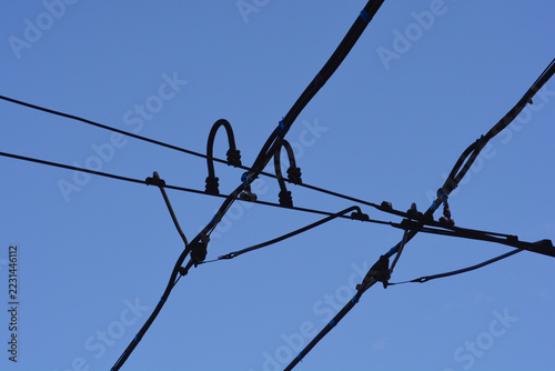 Fotografie Silhouette of an electric tramway overhead contact line intersection system with crossover wires against a clear blue sky