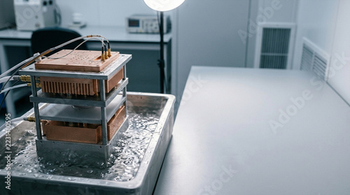 Multi layered copper heat sink test rig submerged in boiling dielectric fluid for advanced two phase liquid immersion cooling research in a hardware engineering laboratory