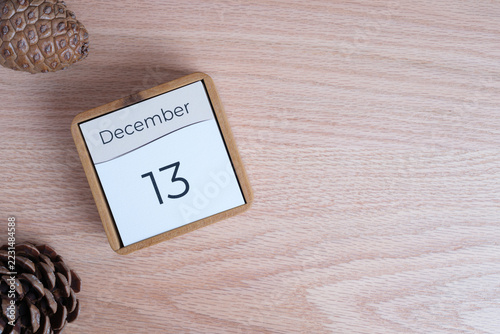 December 13 calendar with pine cones on a light wooden background