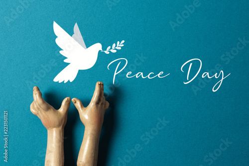 Peace Day Concept with White Dove, Olive Branch and Wooden Hands on Turquoise Background