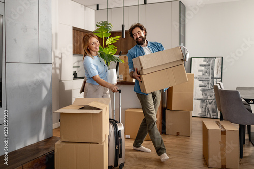 Couple carrying moving boxes into their new apartment during a home move