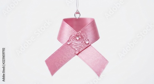 Pink awareness ribbon with water drops falling on white background