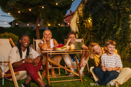 Fotografie Group of friends enjoying a summer evening gathering in backyard with food