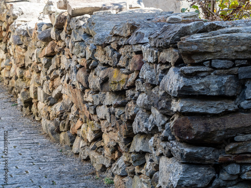 Fotografie Textured stone wall alongside a paved path