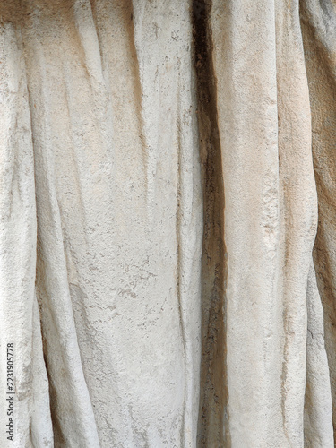 Abstract background. Fragment of carved stone drapery (folds of toga or chiton) from classical ancient sculpture. Close-up
