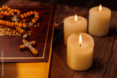 Obraz na plátně Close up of a purple bible and white candles with an olive wood rosary for christian prayer and religious devotion and holy faith